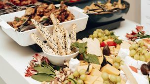 A mouth-watering assortment of cheeses, breadsticks, and fruits in a buffet setting. Perfect for catering events.